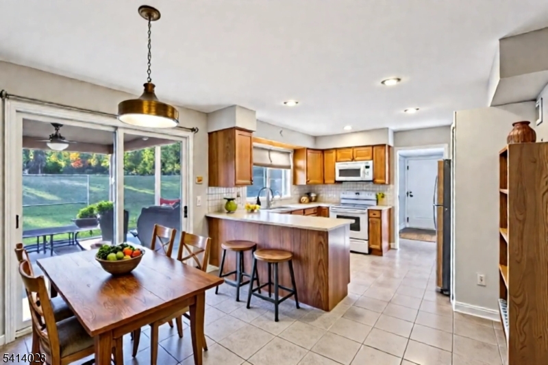 a room with stainless steel appliances kitchen island granite countertop a dining table chairs and a view of living room
