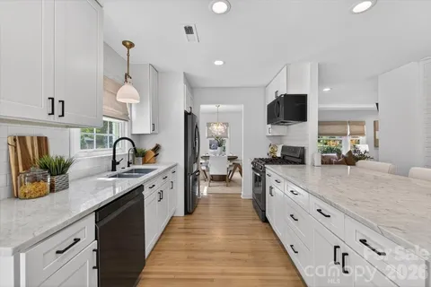 a large kitchen with stainless steel appliances granite countertop a sink counter space and a view of living room