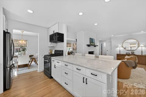a kitchen with granite countertop a sink dishwasher stove and white cabinets with wooden floor