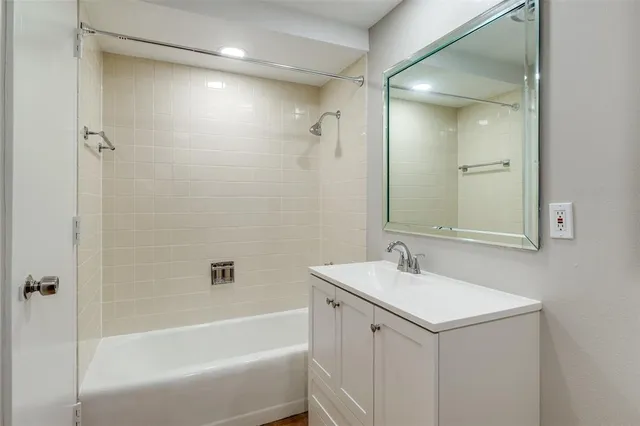 a bathroom with a tub sink double vanity and mirror