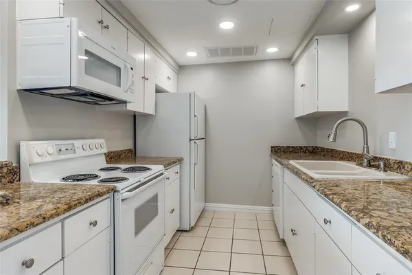 a view of an empty room with kitchen and window