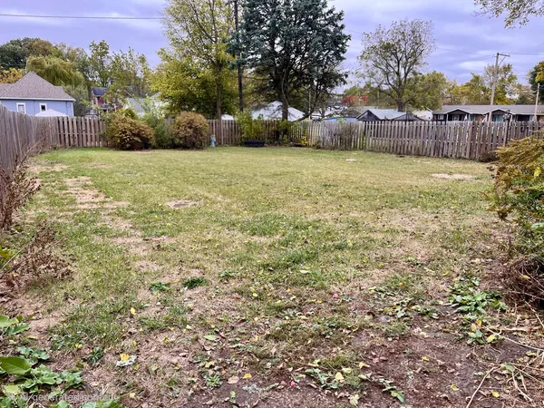 a view of a yard with plants and wooden fence