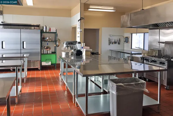 a dining room with stainless steel appliances kitchen island granite countertop a table chairs and a refrigerator