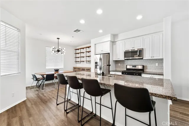 a kitchen with granite countertop a counter space chairs stainless steel appliances and cabinets