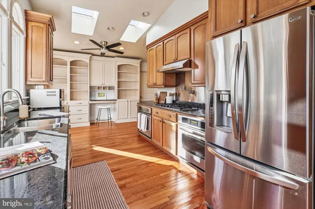 a kitchen with stainless steel appliances granite countertop a refrigerator a stove and a sink