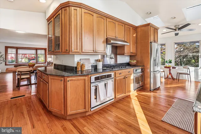 a kitchen with stainless steel appliances granite countertop a stove a sink and a granite counter tops with a large window