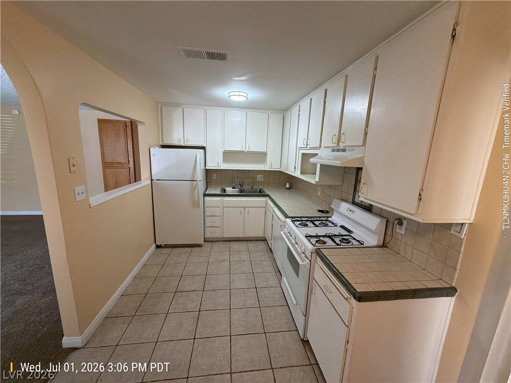 2313 Ragland Street Las Vegas, NV 89108 - Photo 4 of 11 A functional kitchen provides ample cabinetry, a gas range, and a pass-through window to adjacent living space.
