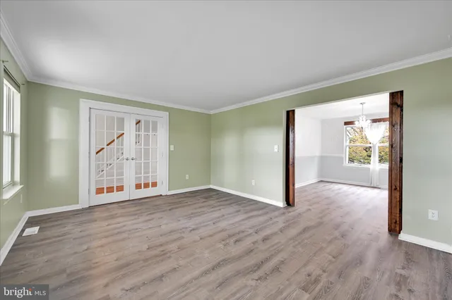 a view of an empty room with glass door and wooden floor