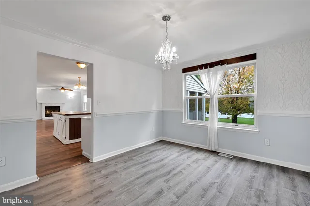 a view of an empty room with kitchen and window