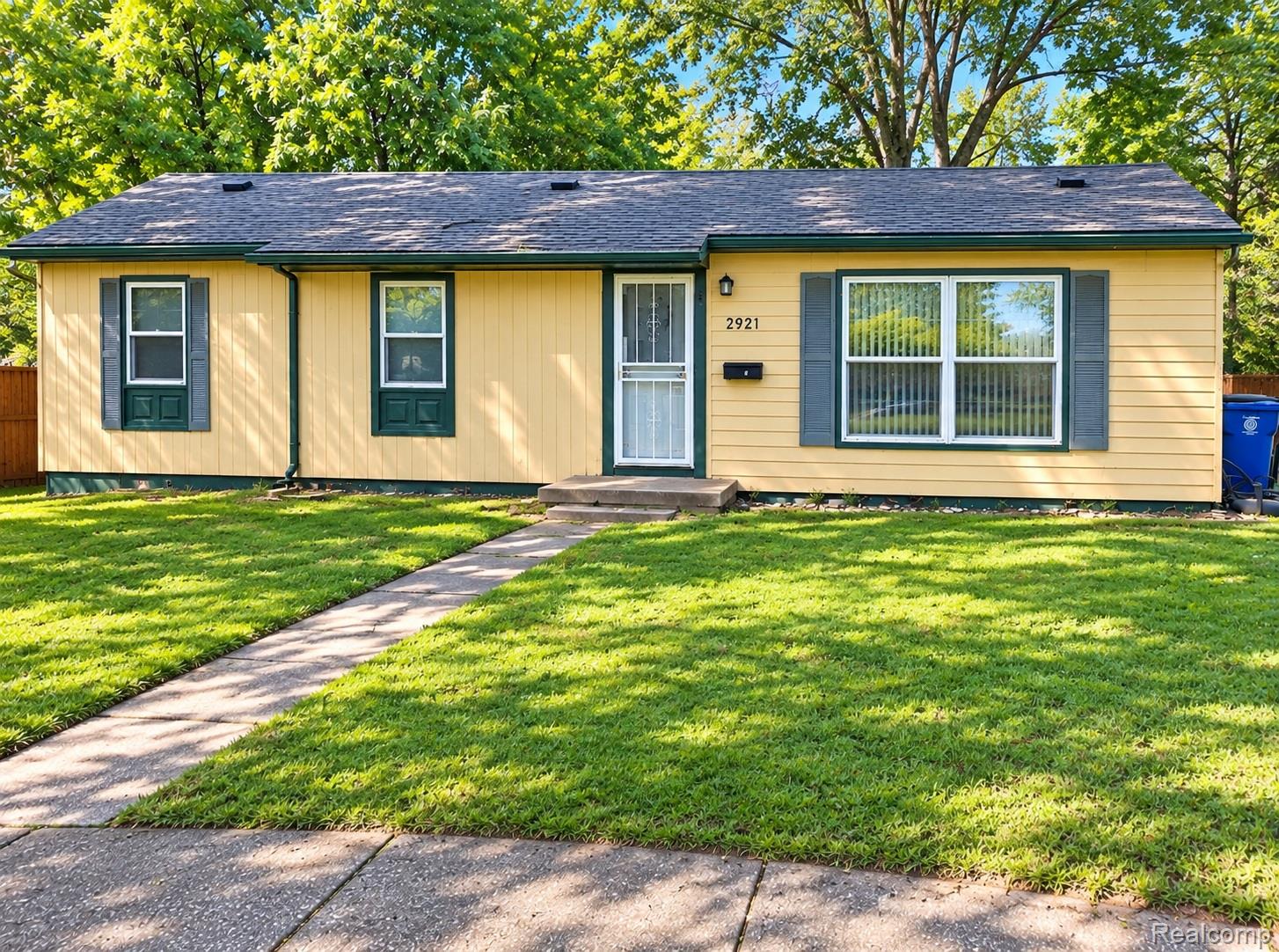 Yellow siding exterior with a dark shingle roof