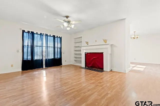 a view of empty room with wooden floor and fireplace