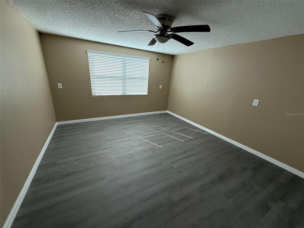 6104 Seabreeze Drive Port Richey, FL 34668 - Photo 12 of 25 an empty room with wooden floor chandelier fan and windows