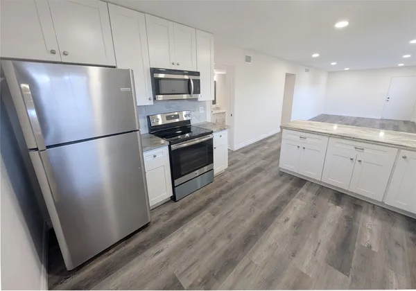 a kitchen with granite countertop a refrigerator stove and microwave