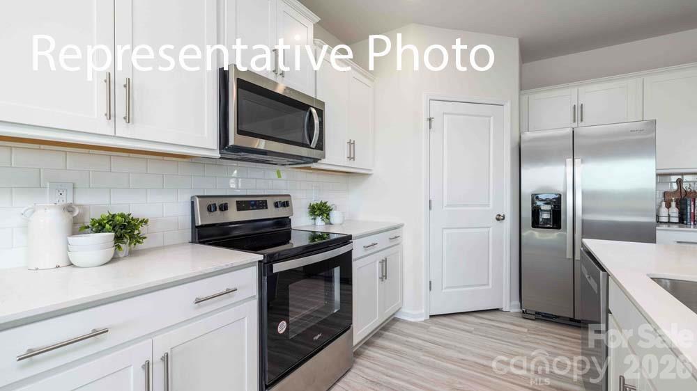 7592 Bainbridge Road Sherrills Ford, NC 28673 - Photo 7 of 28 a kitchen with stainless steel appliances granite countertop a refrigerator a stove a microwave oven with white cabinets and wooden floor