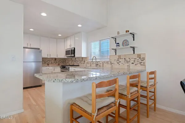 a kitchen with stainless steel appliances granite countertop a sink and a refrigerator