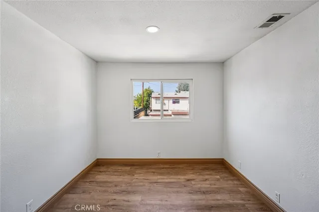 a view of an empty room with a window and wooden floor