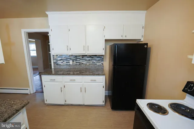 a kitchen with granite countertop white cabinets and refrigerator