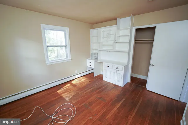 a view of empty room with wooden floor and window