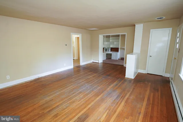a view of an empty room with wooden floor and a window