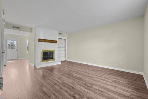 a view of empty room with wooden floor and fireplace