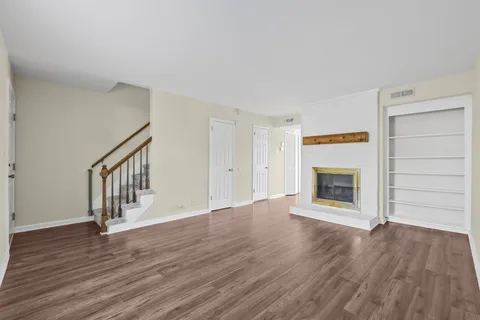 a view of an empty room with wooden floor fireplace and a window