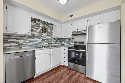 a kitchen with granite countertop a refrigerator sink and cabinets