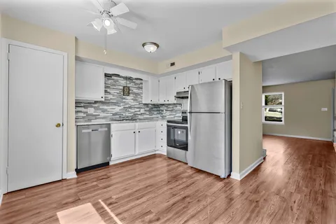 a kitchen with a refrigerator cabinets and wooden floor