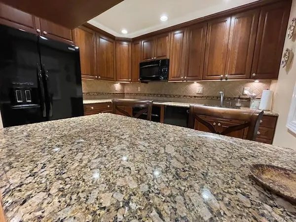 a kitchen with stainless steel appliances kitchen island granite countertop a refrigerator a stove top oven a sink and dishwasher