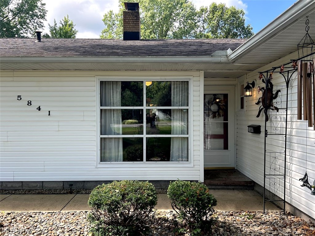 5841 Horning Road Kent, OH 44240 - Photo 21 of 31 White siding exterior featuring a multi-pane window, covered entry, and brick chimney