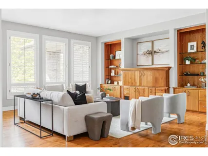 a living room with furniture a large window and wooden floor