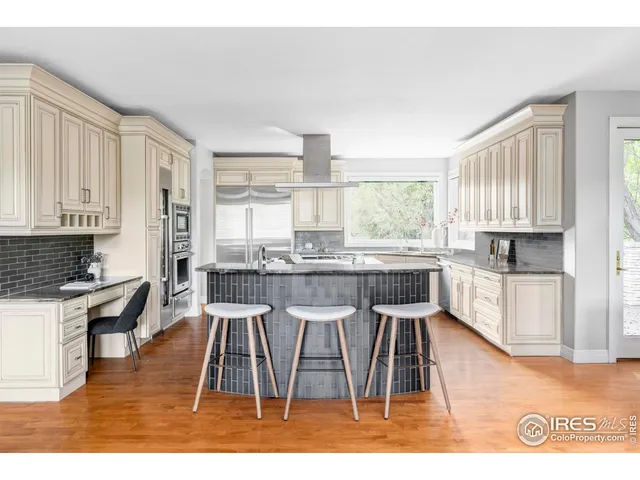 a dining room with kitchen island granite countertop wooden floors and a view of living room