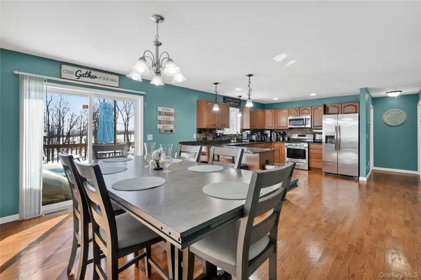 a dining room with stainless steel appliances kitchen island granite countertop a dining table chairs and a refrigerator