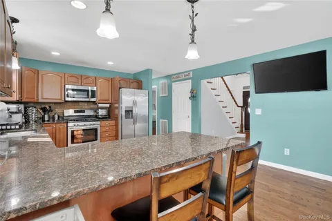 a kitchen with stainless steel appliances granite countertop a refrigerator a stove top oven a sink with island and chairs