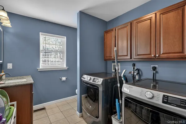 a utility room with stainless steel appliances wooden cabinets washer and dryer