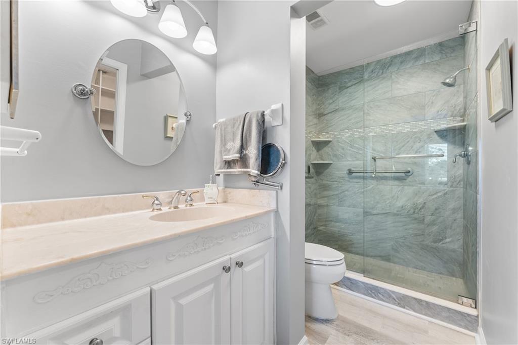 5928 Cranbrook Way, Unit D202 Naples, FL 34112 - Photo 9 of 23 Full bath with a shower stall, wood finished floors, vanity, toilet, and visible vents