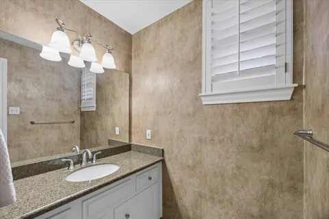 a bathroom with a granite countertop sink a mirror and a shower
