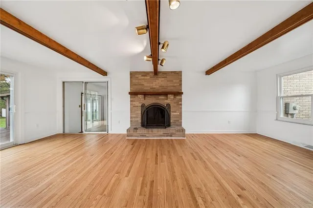 a view of empty room with fireplace and wooden floor