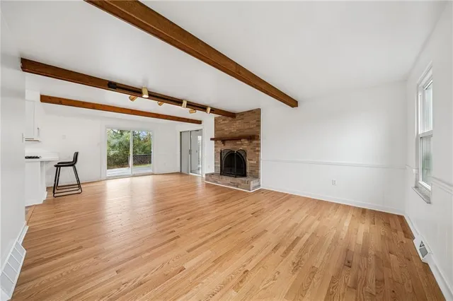 a view of empty room with wooden floor and fireplace