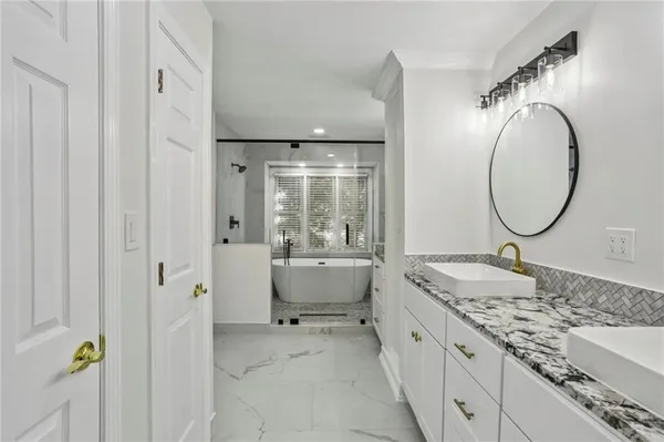 a spacious bathroom with a granite countertop sink mirror and a bathtub