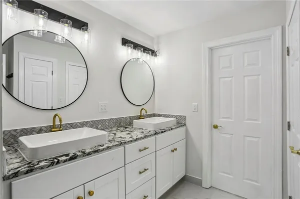 a bathroom with a granite countertop double vanity sinks and a mirror