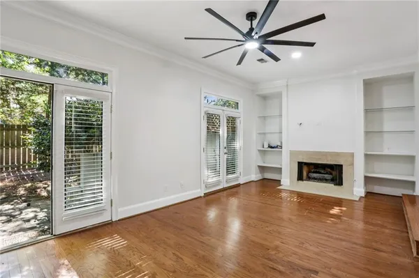 an empty room with windows fireplace and a kitchen space