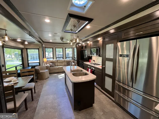 a room with stainless steel appliances kitchen island granite countertop a refrigerator and a stove