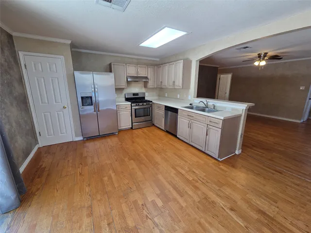 a large kitchen with a sink dishwasher a refrigerator and wooden floor