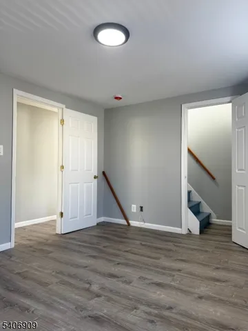 an empty room with wooden floor and staircase