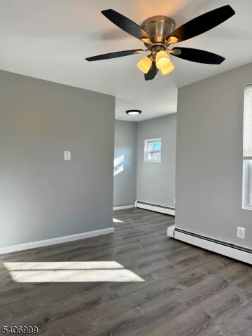 a view of an empty room with window and wooden floor