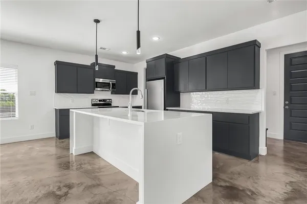 a kitchen with kitchen island a stove a sink a refrigerator and chairs