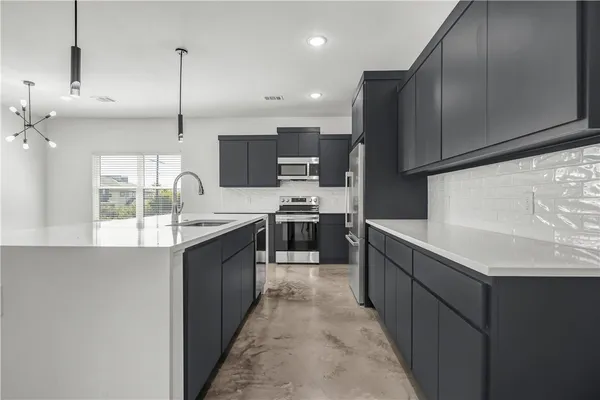 a large kitchen with stainless steel appliances kitchen island granite countertop a sink a stove and a refrigerator