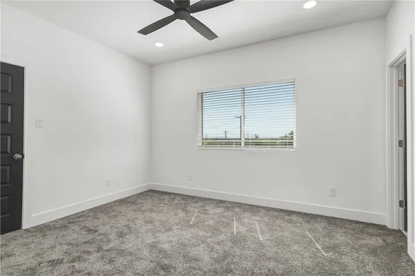 an empty room with a window and ceiling fan