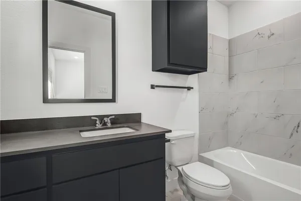 a bathroom with a sink toilet vanity mirror and bathtub