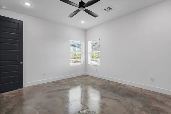 an empty room with windows and ceiling fan
